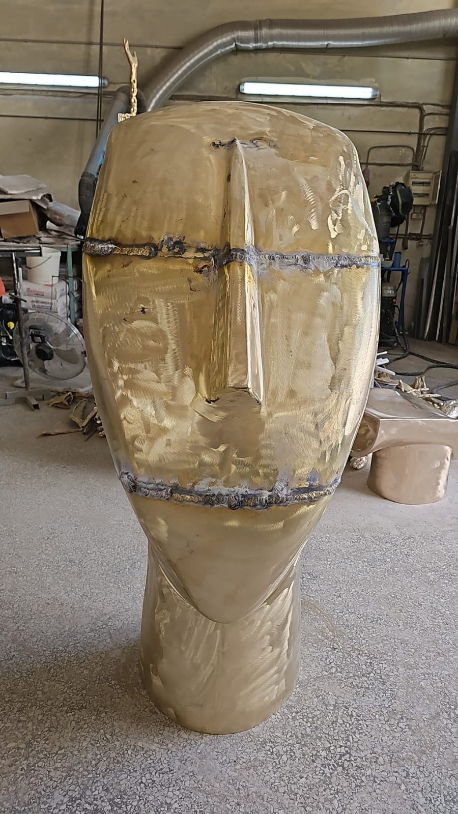Front view of the monumental bronze form with assembly seams still visible in the workshop
